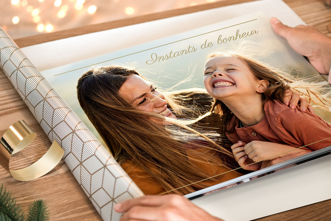 2 mains emballant un album photo personnalisé dans un papier cadeau