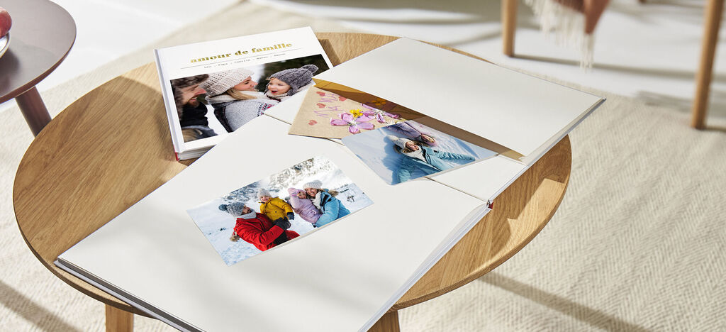Un livre photo posé sur une table basse avec des images insérée dans la pochette souvenir du livre