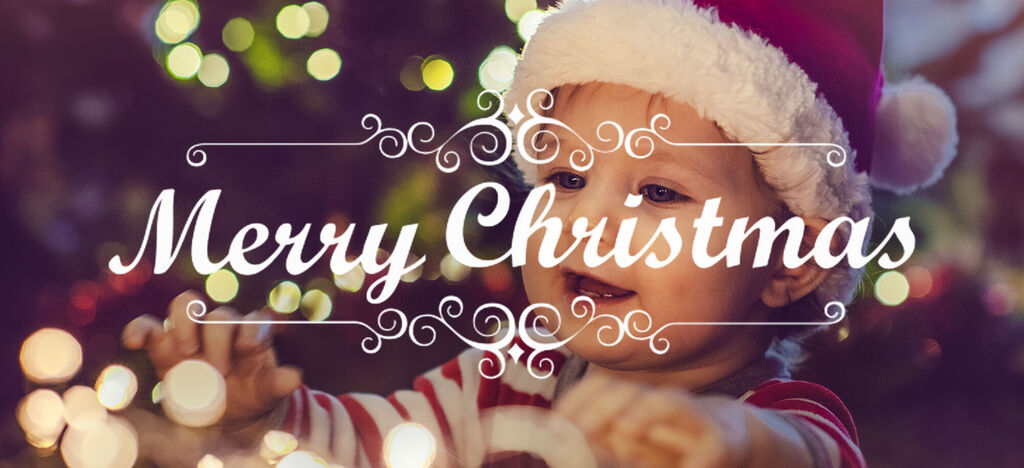 Un enfant avec un bonnet de Noël joue avec des lumières. En arrière-plan, des lumières de Noël brillent.