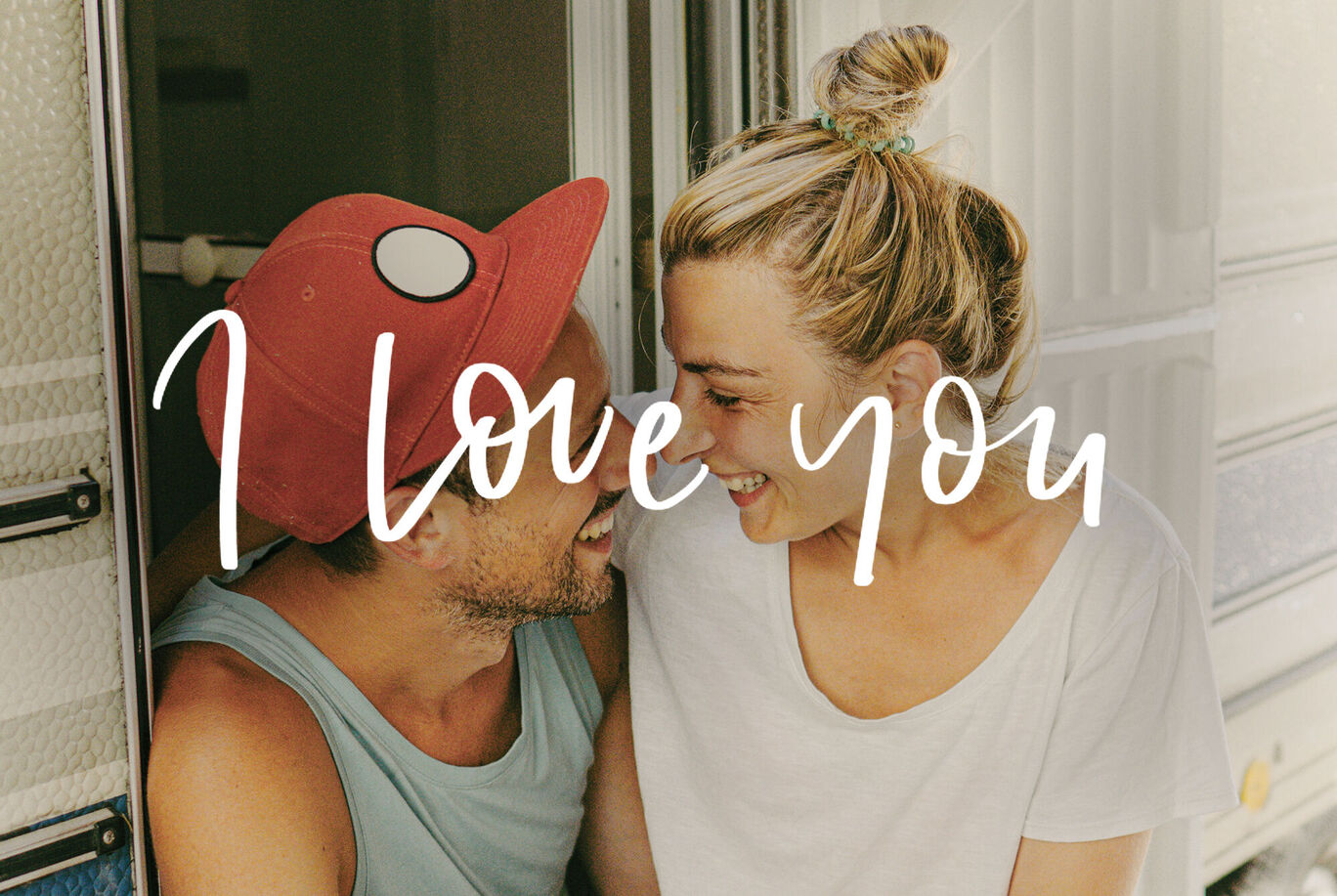 Un couple assis ensemble dans un camping-car profite d'un beau moment. Texte 'I Love You' au-dessus de l'image.
