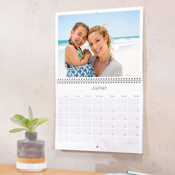 Calendrier photo double-page ouvert sur le mois de juillet et accroché au mur