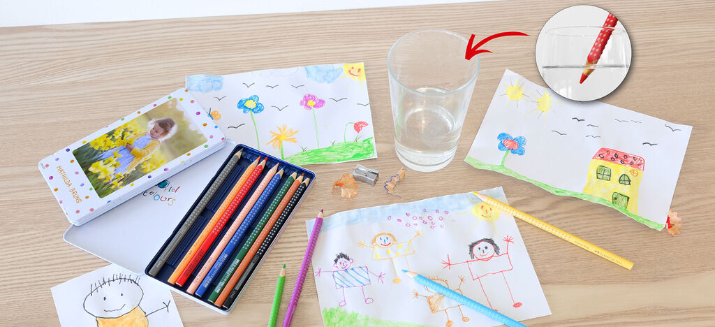 Une table avec des dessins colorés, des crayons et un verre d'eau.