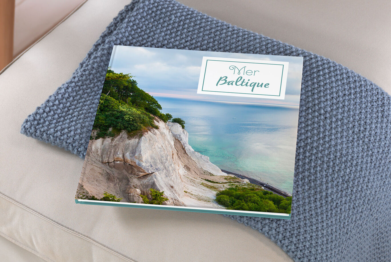 Grand album carré posé sur un canapé avec une photo de la mer Baltique