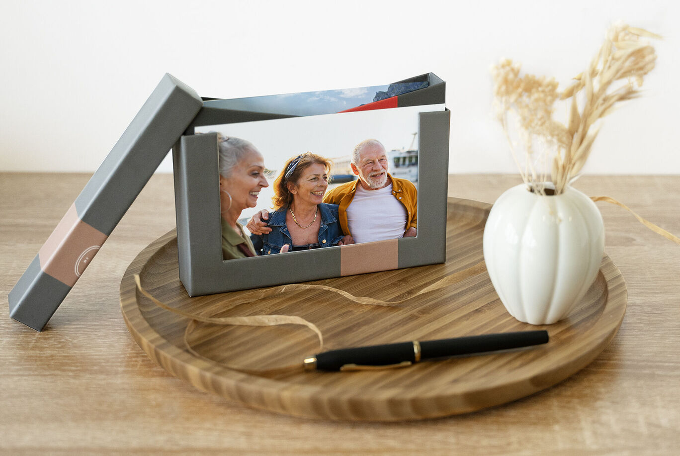 Un porte-photo affectueux avec une image d'amis, un vase stylé et un stylo sur un plateau en bois.