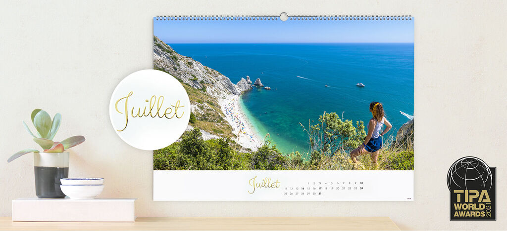 Une femme regarde un paysage côtier spectaculaire dans le calendrier de juillet.