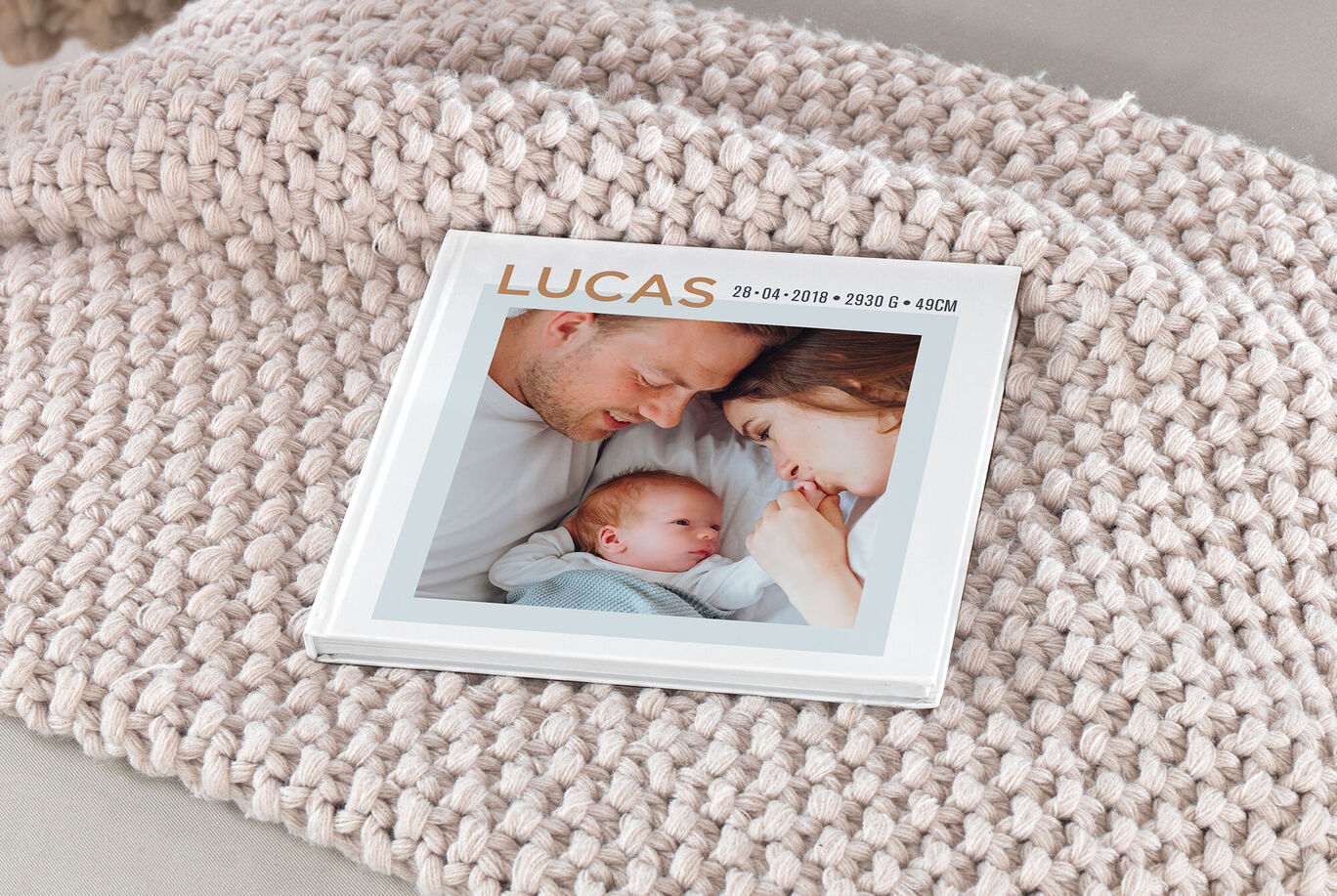 Album photo carré posé sur une couverture avec la photo d'un bébé