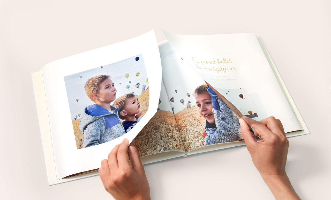 Livre Photo CEWE avec des mains en train d'ouvrir la double page panoramique