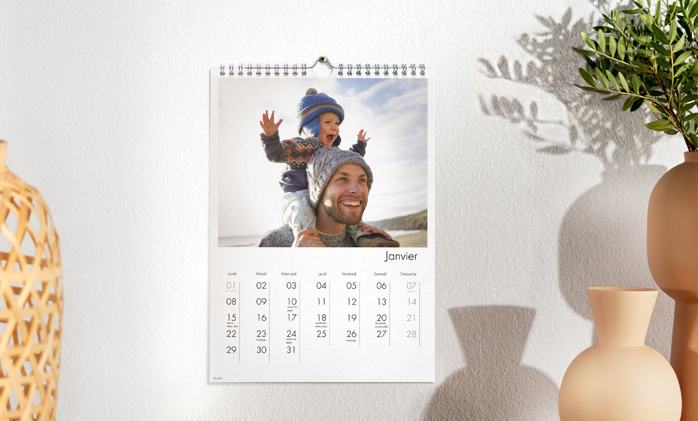 Un calendrier photo A4 portrait accroché au mur avec la photo d'un enfant sur les épaules de son papa