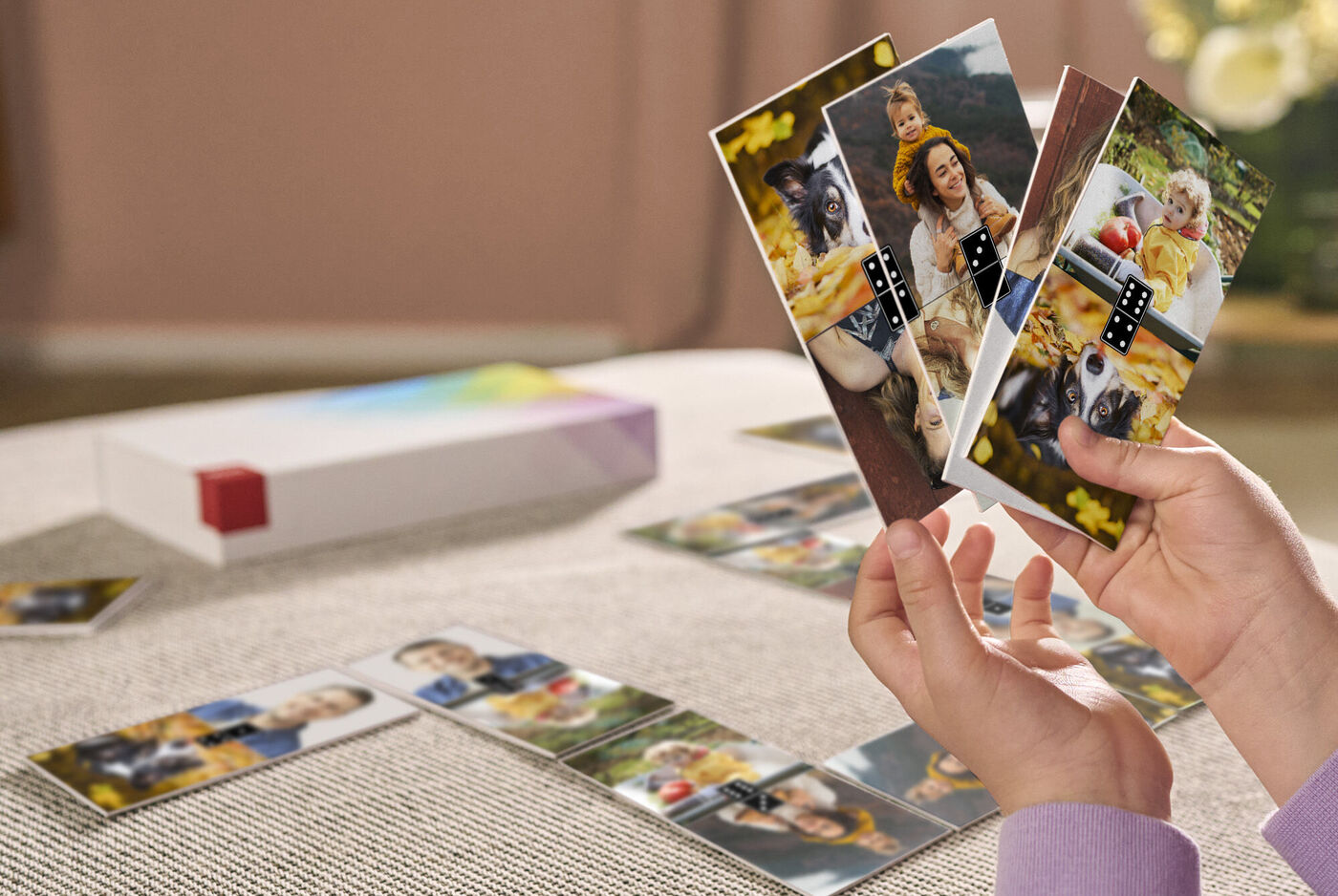 Une personne tient plusieurs cartes photo colorées dans ses mains. Une boîte est visible en arrière-plan.