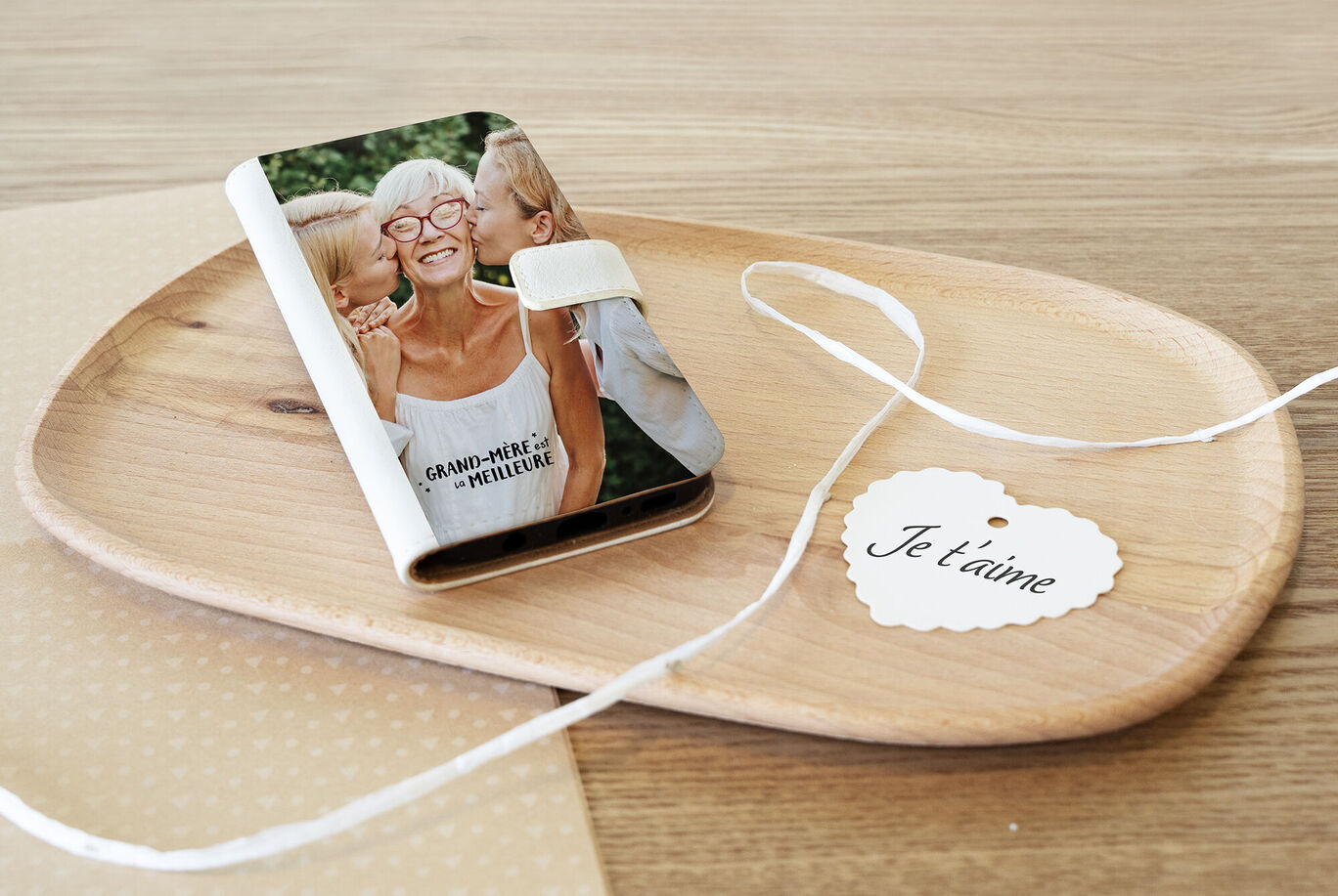 Un album photo CEWE affectueux sur un plateau en bois, affichant un message romantique et des éléments décoratifs.