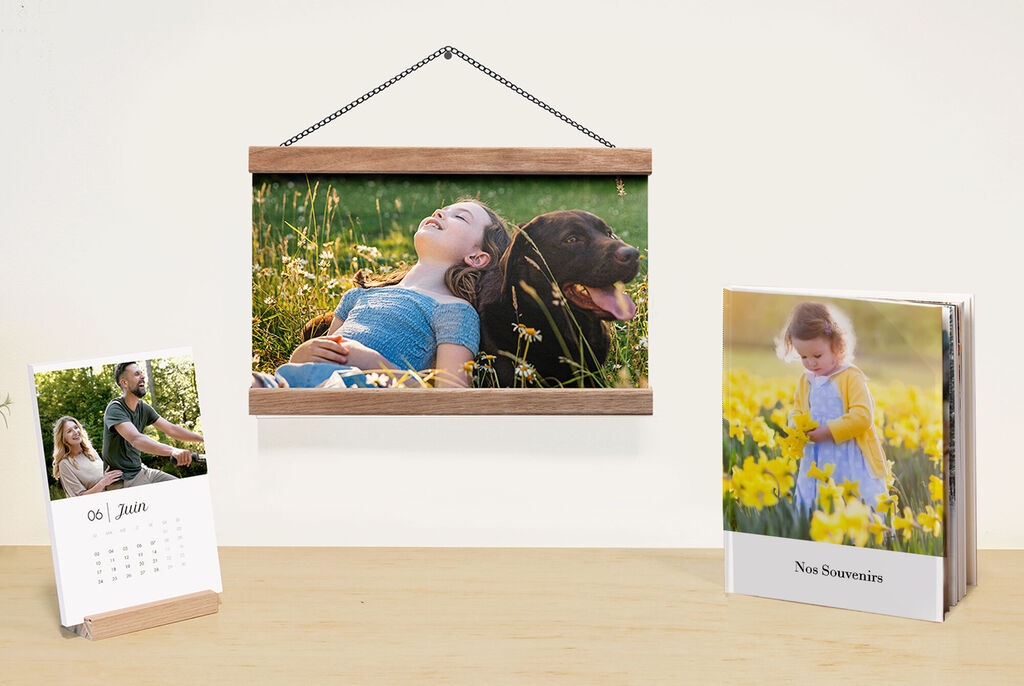 Un magnifique calendrier mural et un livre photo CEWE sur une table. Un tableau accroché représente une scène naturelle.