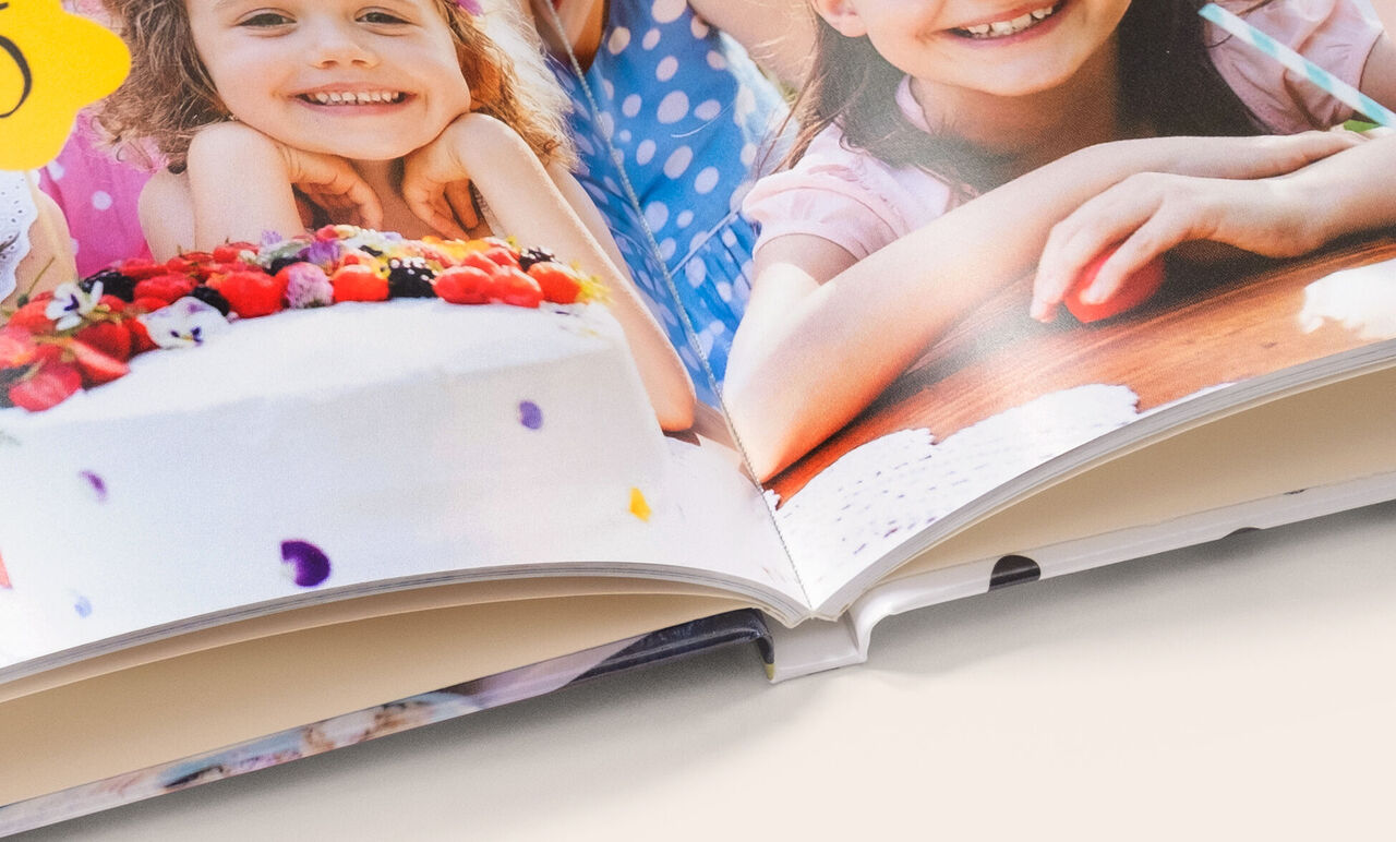 Zoom sur la reliure d'un album photo A5 paysage ouvert et avec reliure classique montrant des photos d'enfants