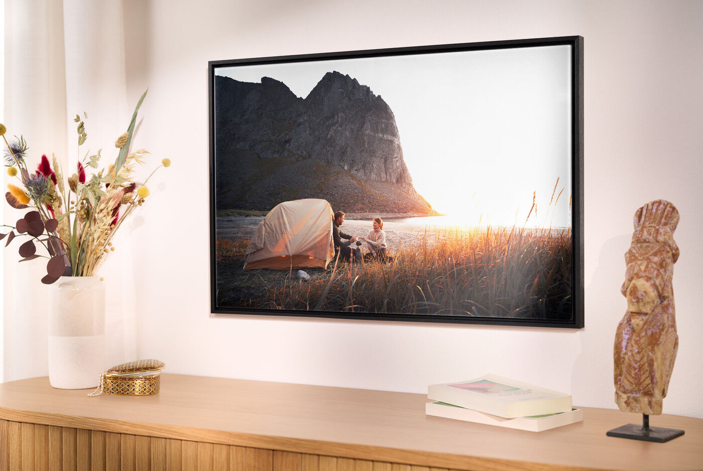 Une tente se tient au bord d'un lac avec un groupe de personnes au coucher de soleil.