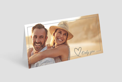 Deux personnes à l’extérieur dans une étreinte amicale, avec un chapeau de soleil, fond de plage.