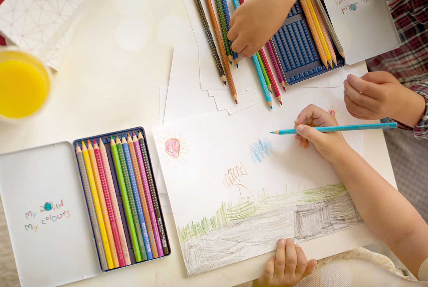 Boîte Faber-Castell personnalisée et un enfant qui fait un dessin au crayon de couleur