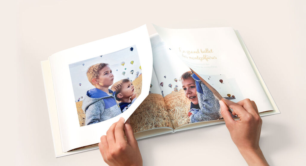 Livre Photo CEWE avec des mains en train d'ouvrir la double page panoramique
