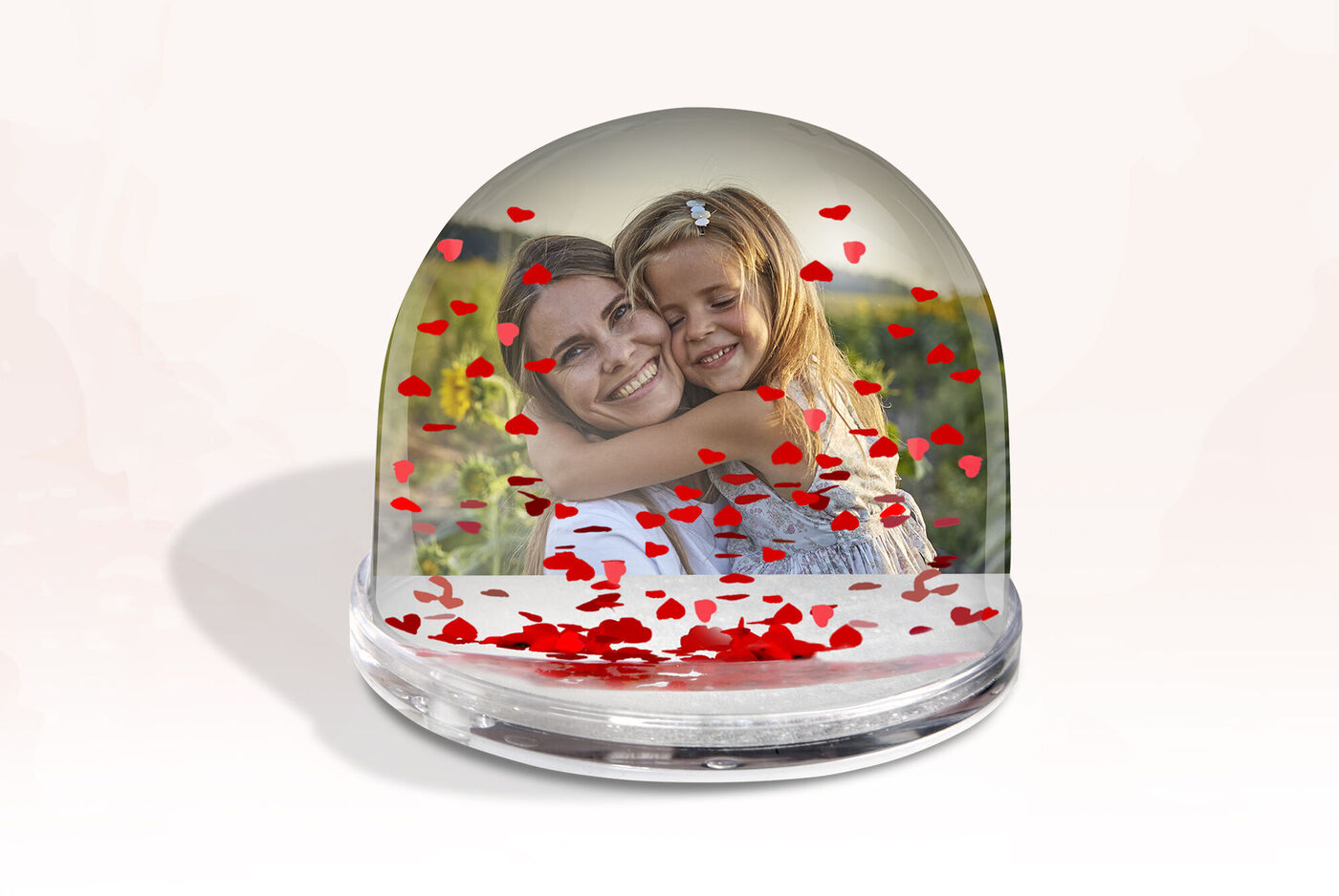 Deux enfants s'embrassent dans un globe à neige heureux, entourés de cœurs rouges