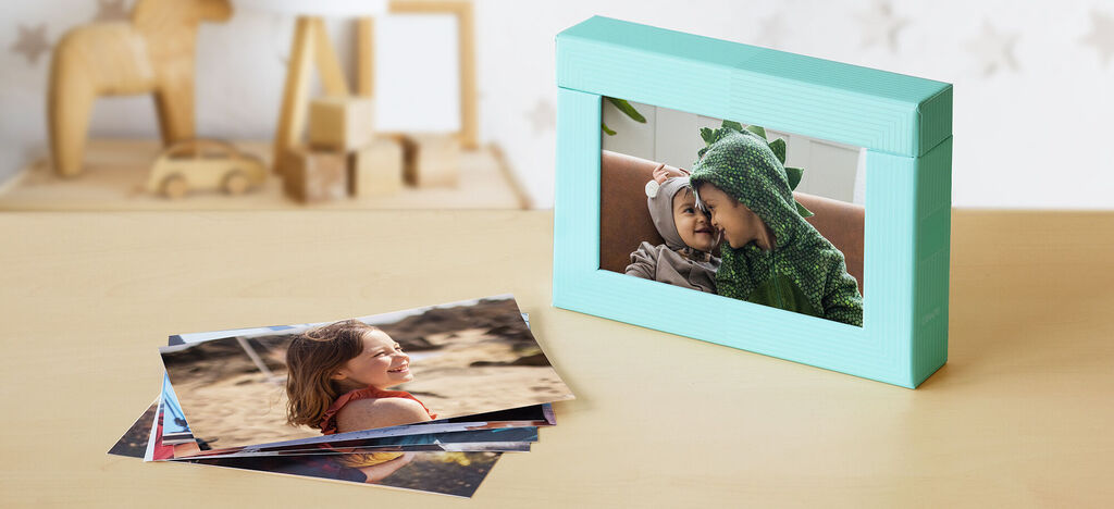 Un album photo soigneusement conçu en turquoise avec une image d'une personne en costume de dragon. Plusieurs photos sont étalées sur une table devant l'album.