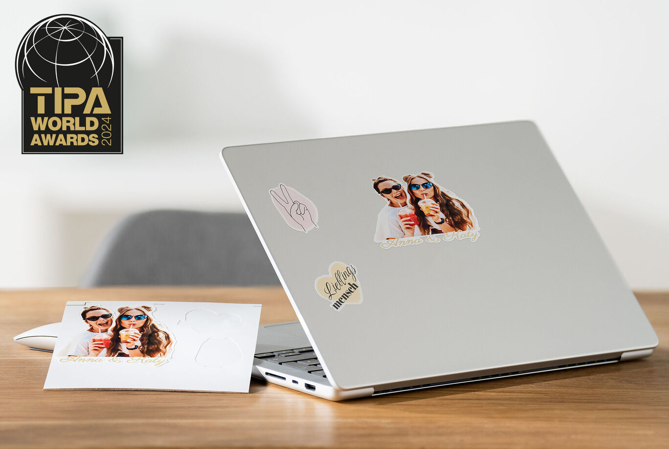 Ordinateur portable avec des autocollants et une carte postale sur une table