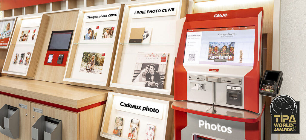 Un kiosque photo CEWE avec des livres photo, calendriers et impressions photo.