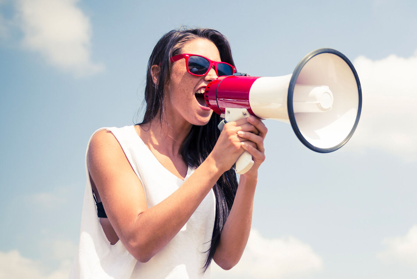 Une personne tient un mégaphone en l'air et parle.